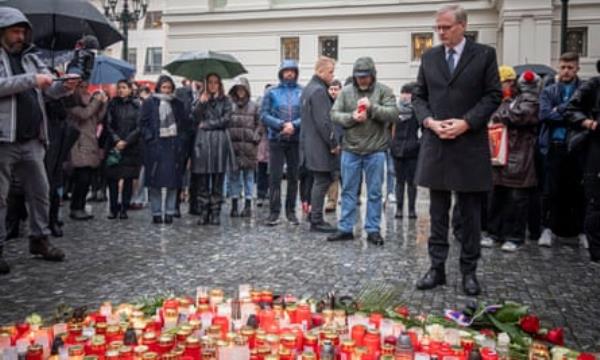 People look on as Petr Fiala stands beside a makeshift memorial