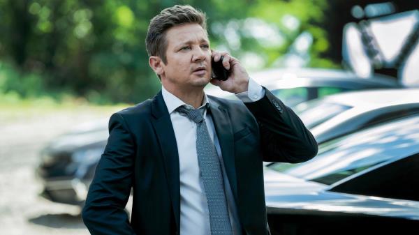 Jeremy Renner in a suit and tie talking on the phone in Mayor of Kingstown