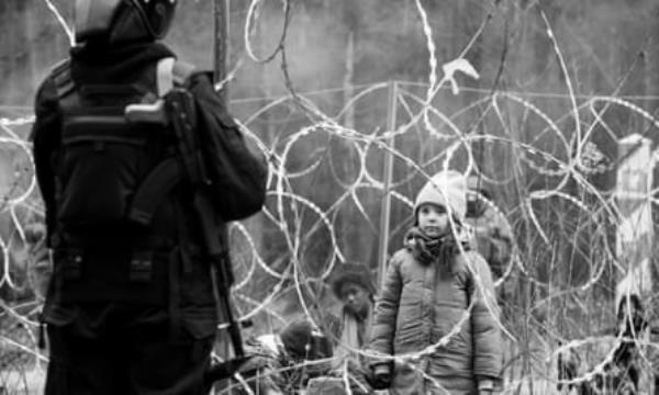 A little girl looks at a man through barbed wire fence.